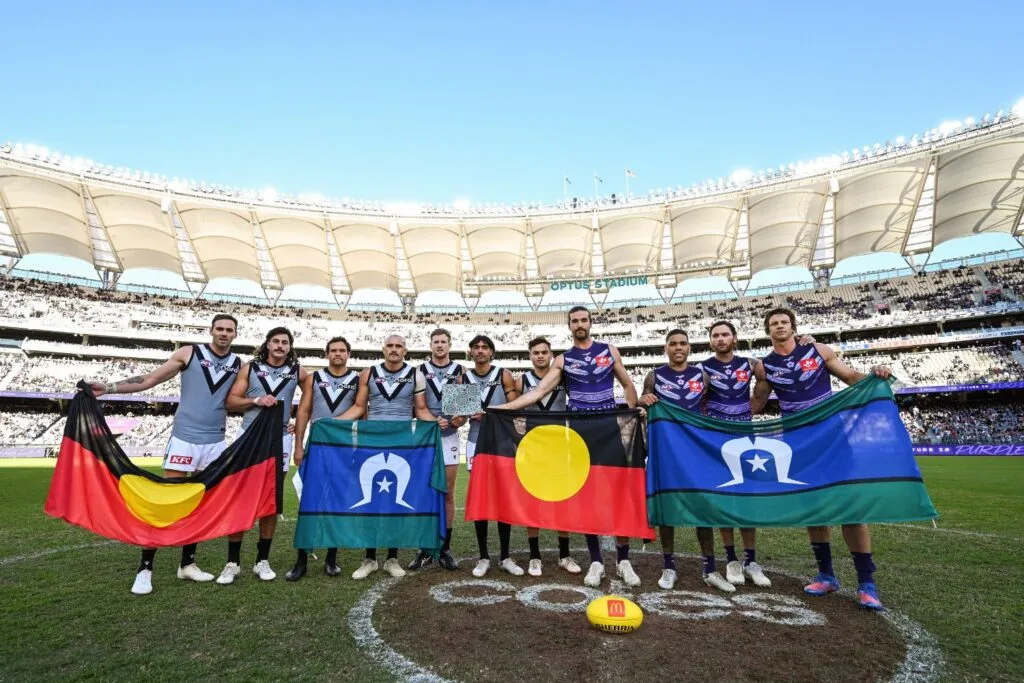 Players change gifts for the start of NAIDOC week during an AFL match.