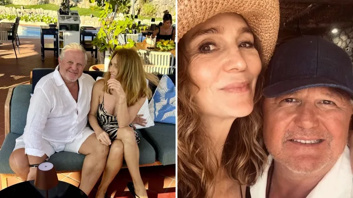 Couple sitting together in a sunny outdoor setting and taking a selfie with a hat and cap.