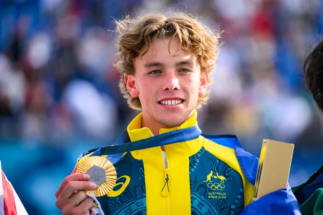 Young athlete in an Australian outfit holding a silver medal at an event.