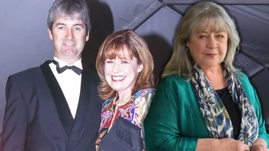 Three people smiling at an event; man in tuxedo, woman in colorful dress, older woman with grey hair in teal outfit.