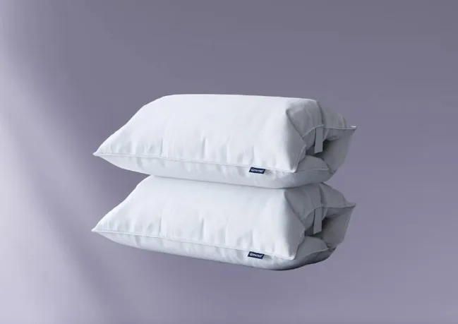 Two stacked white Downy pillows against a gray background.