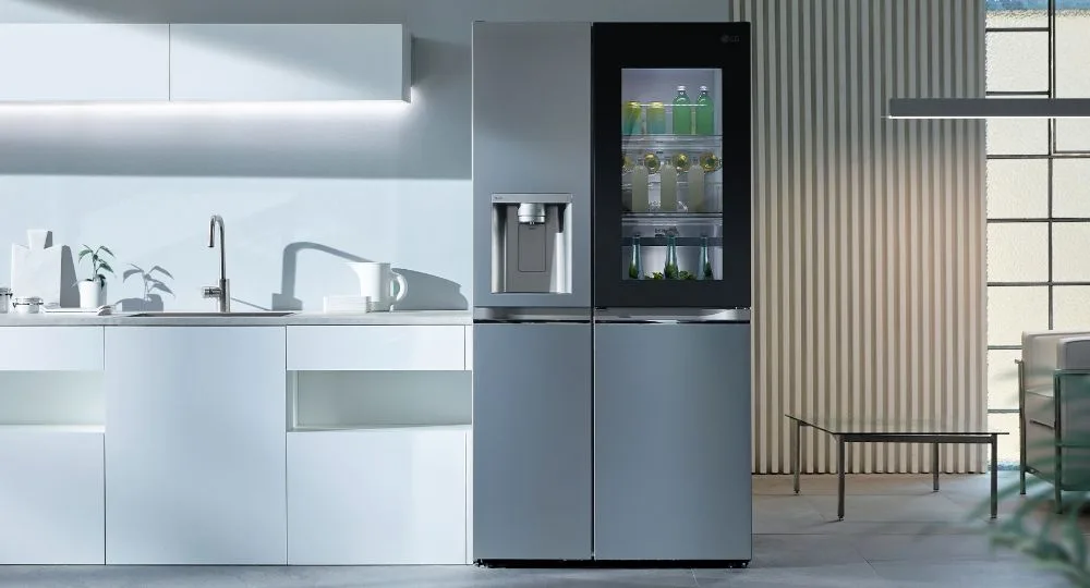 Modern kitchen with a sleek LG refrigerator, showing drinks inside, next to white cabinets and a sink.