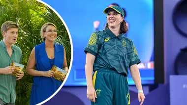 Two people holding cards in a tropical setting; a woman in sports attire stands on stage smiling.