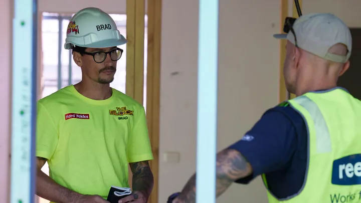"Two construction workers in safety gear discussing inside a building site."