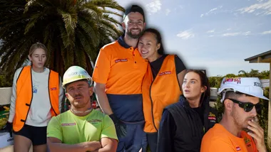 Group of construction workers in orange safety vests, two wearing hard hats, against a backdrop of trees and clear sky.
