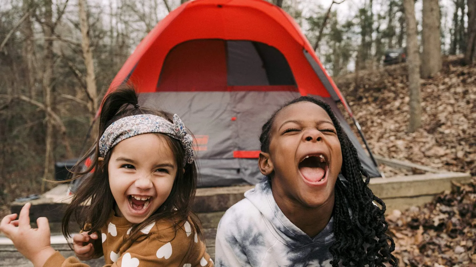 Two girls playing in front of a tent during a camping trip over school holidays.