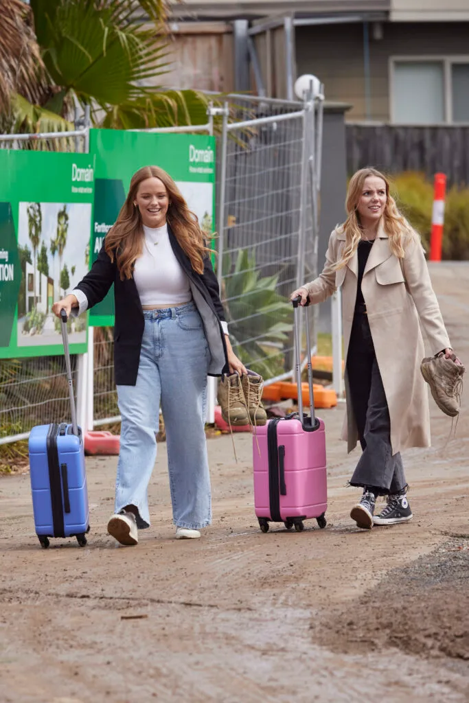 Maddy and Charlotte walking with suitcases into The Block