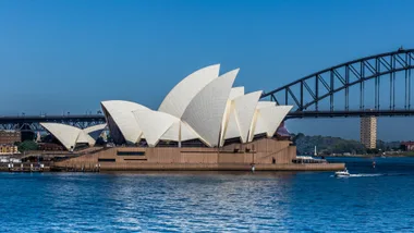 Sydney Opera House with Sydney Harbour Bridge in the background on a clear day, with a boat on the water.