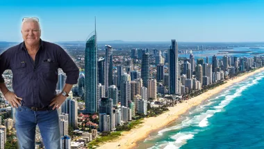 Man standing in front of Gold Coast skyline with high-rise buildings and a beach.