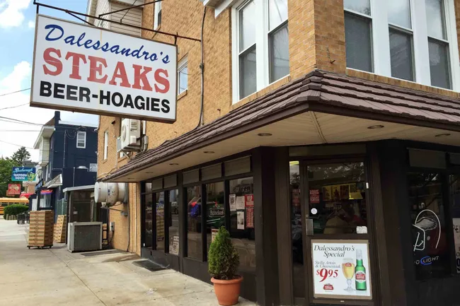 Exterior of Dalessandro's Steaks, a brick building with a sign for steaks, beer, and hoagies.