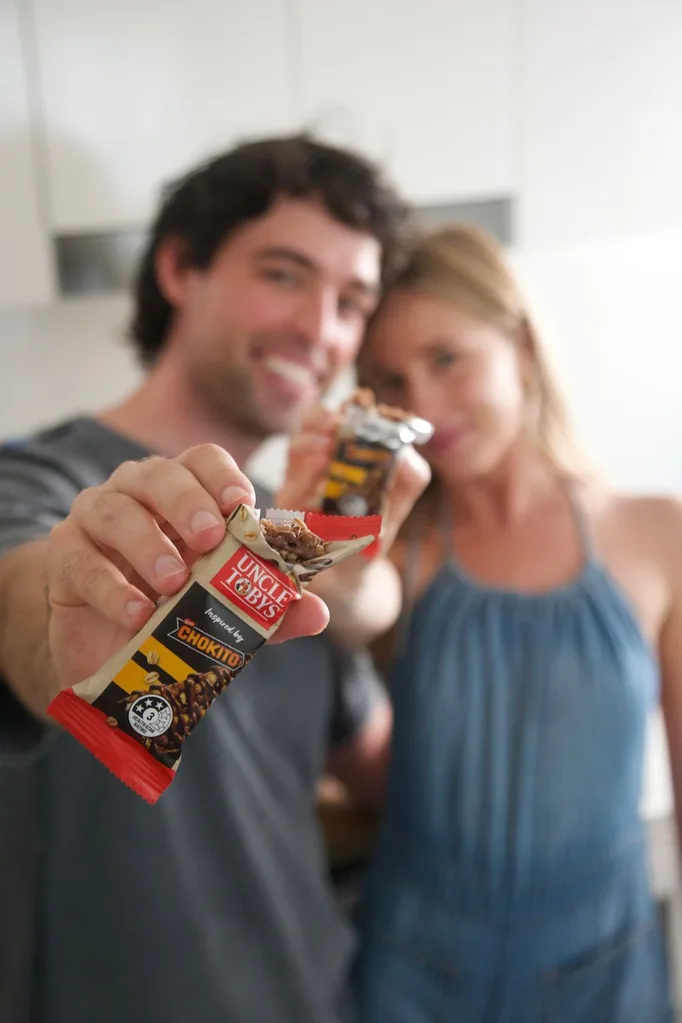 man and woman eating an uncle tobys muesli bar