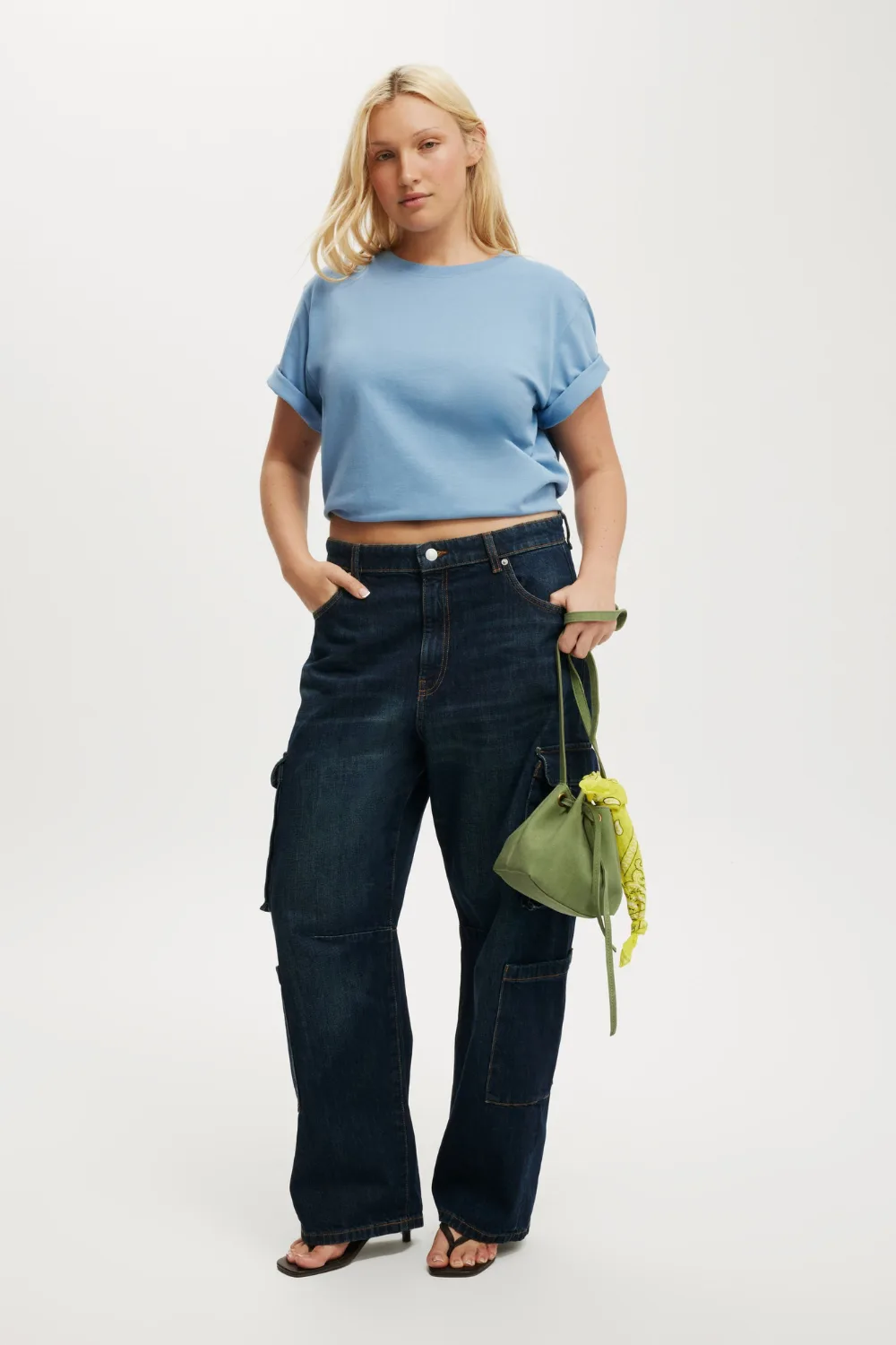 Cotton On model wearing blue t shirt, dark blue jeans and green bag best plus size clothing brands