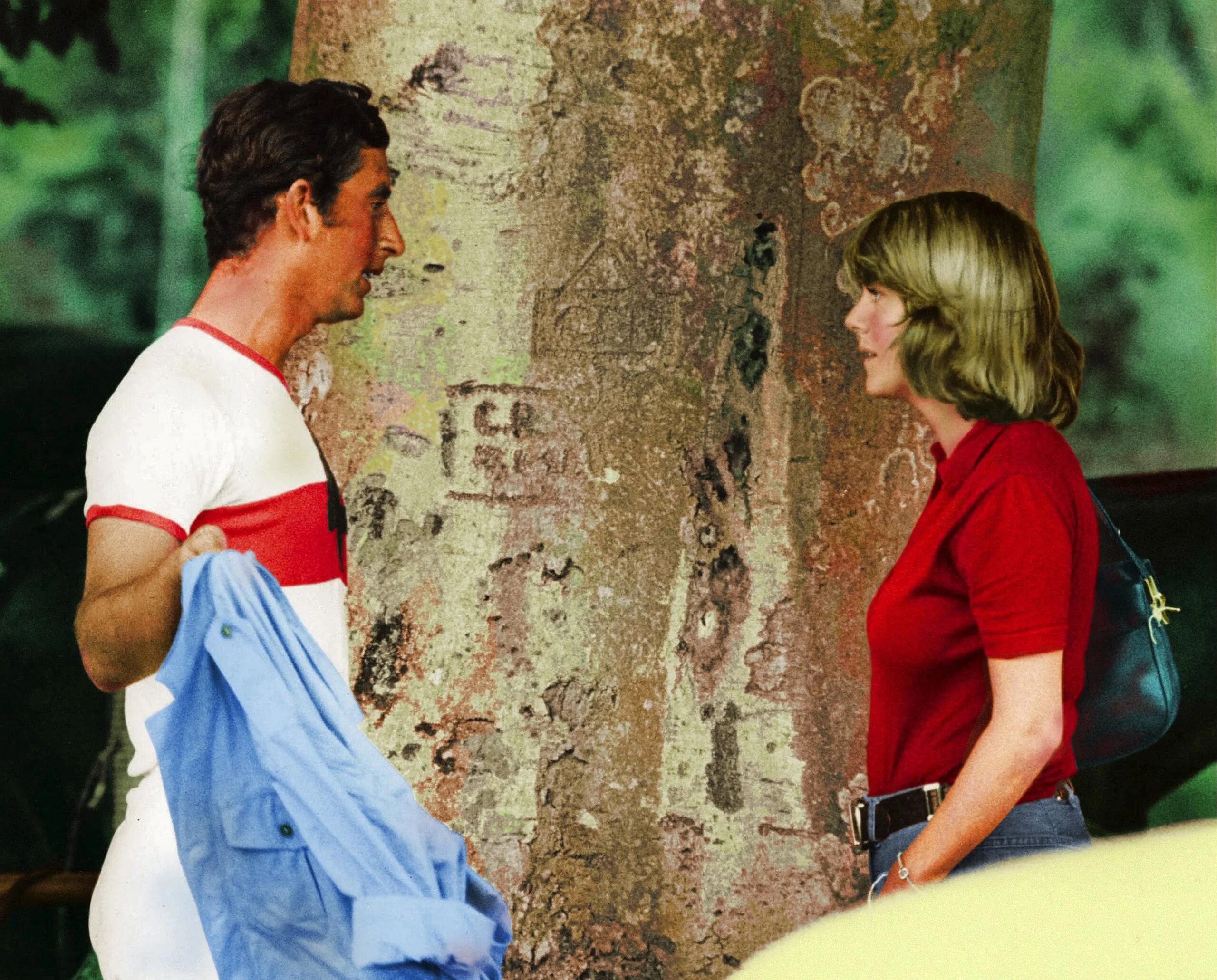 Young Charles and Camilla standing in front of a tree.