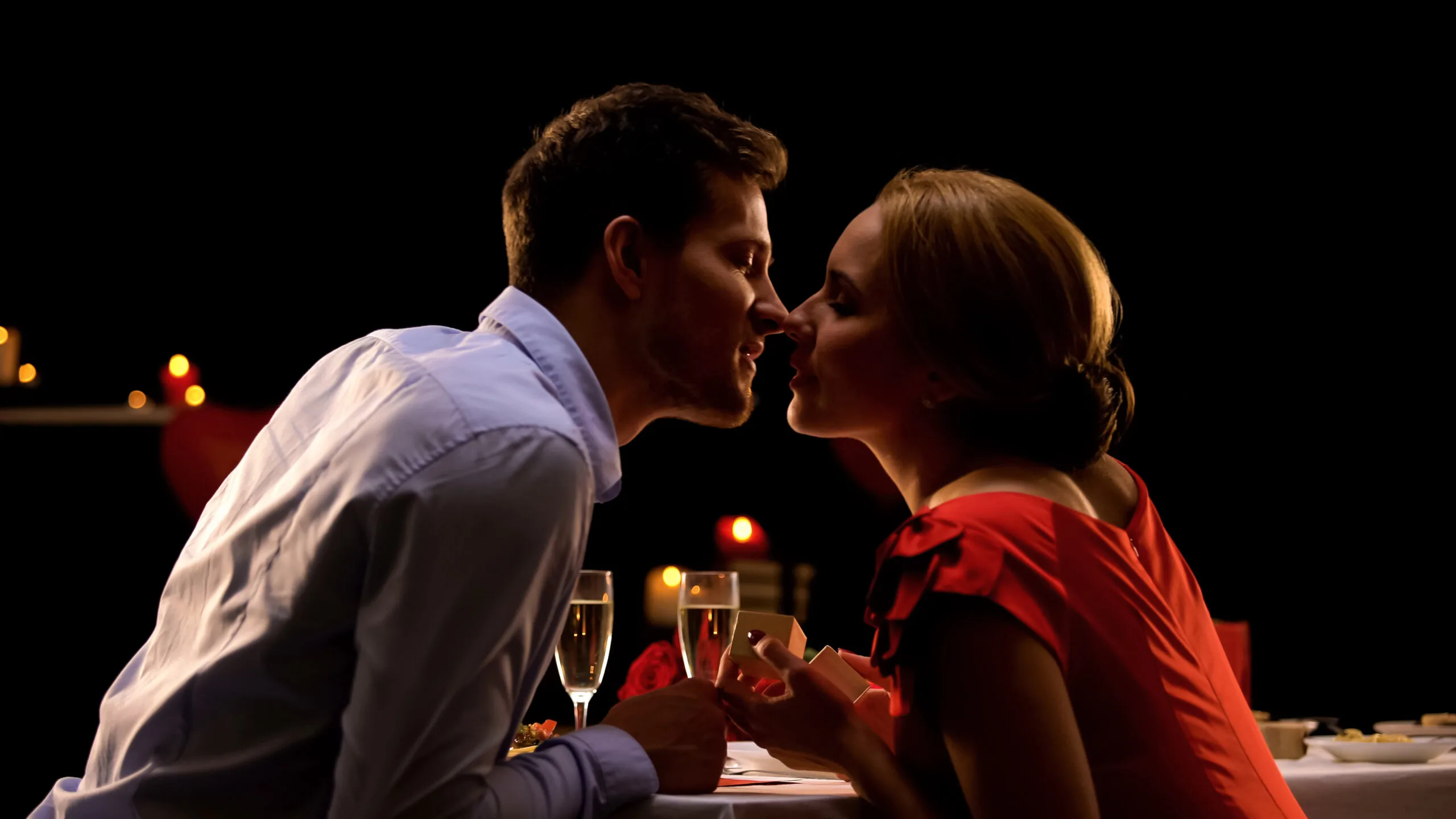 Man and woman leaning in for a kiss at dinner. sex advice