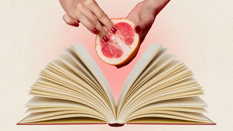 Hands touching grapefruit in front of open book