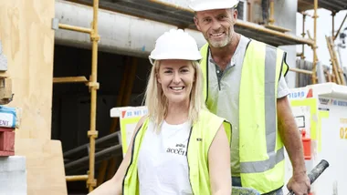 Jess Eva and Norm Hogan on set of The Block wearing high vis vests.