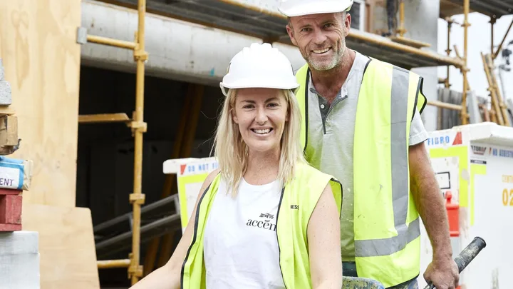 Jess Eva and Norm Hogan on set of The Block wearing high vis vests.