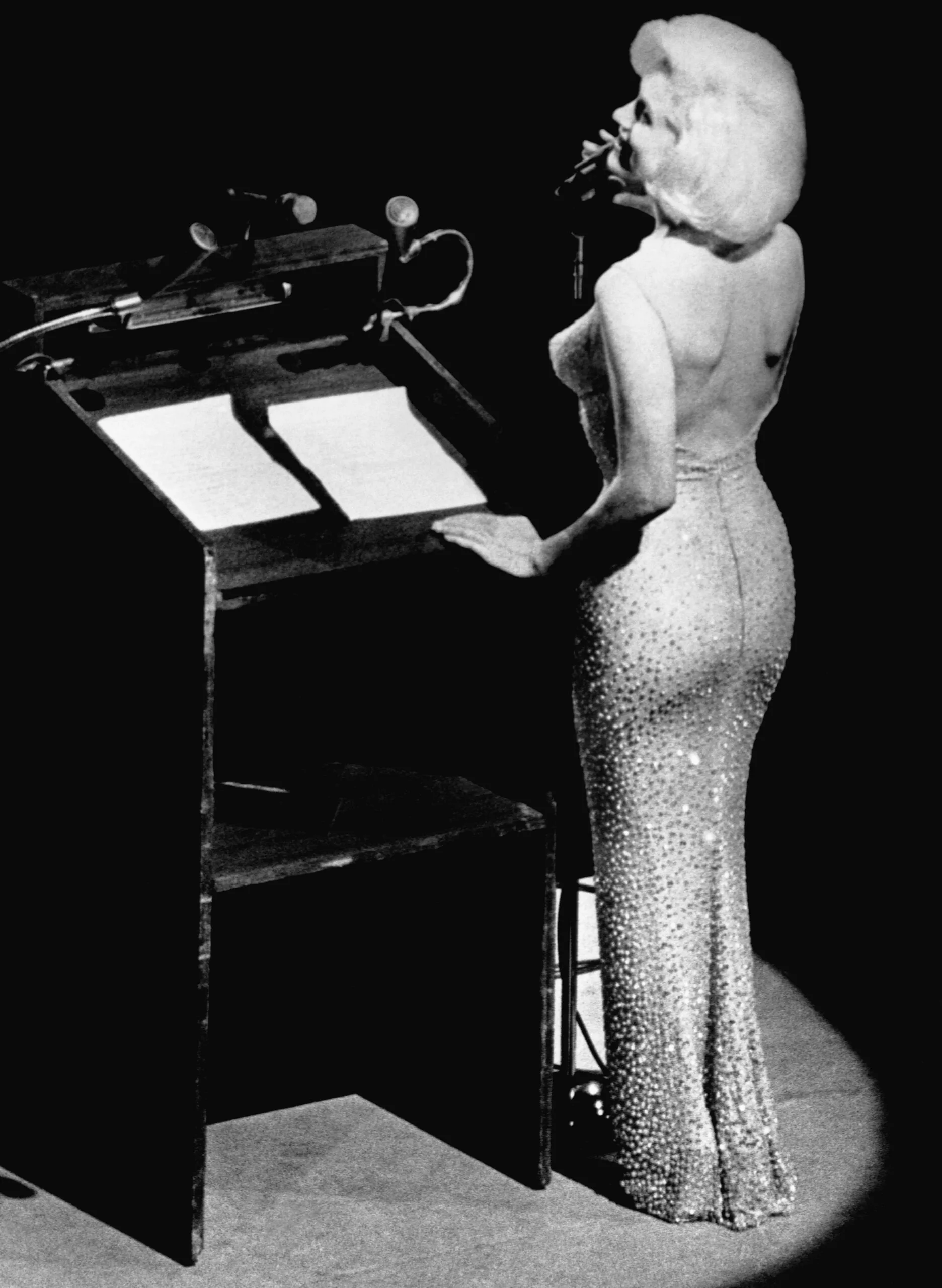 Black and white image of Marilyn Monroe on stage.