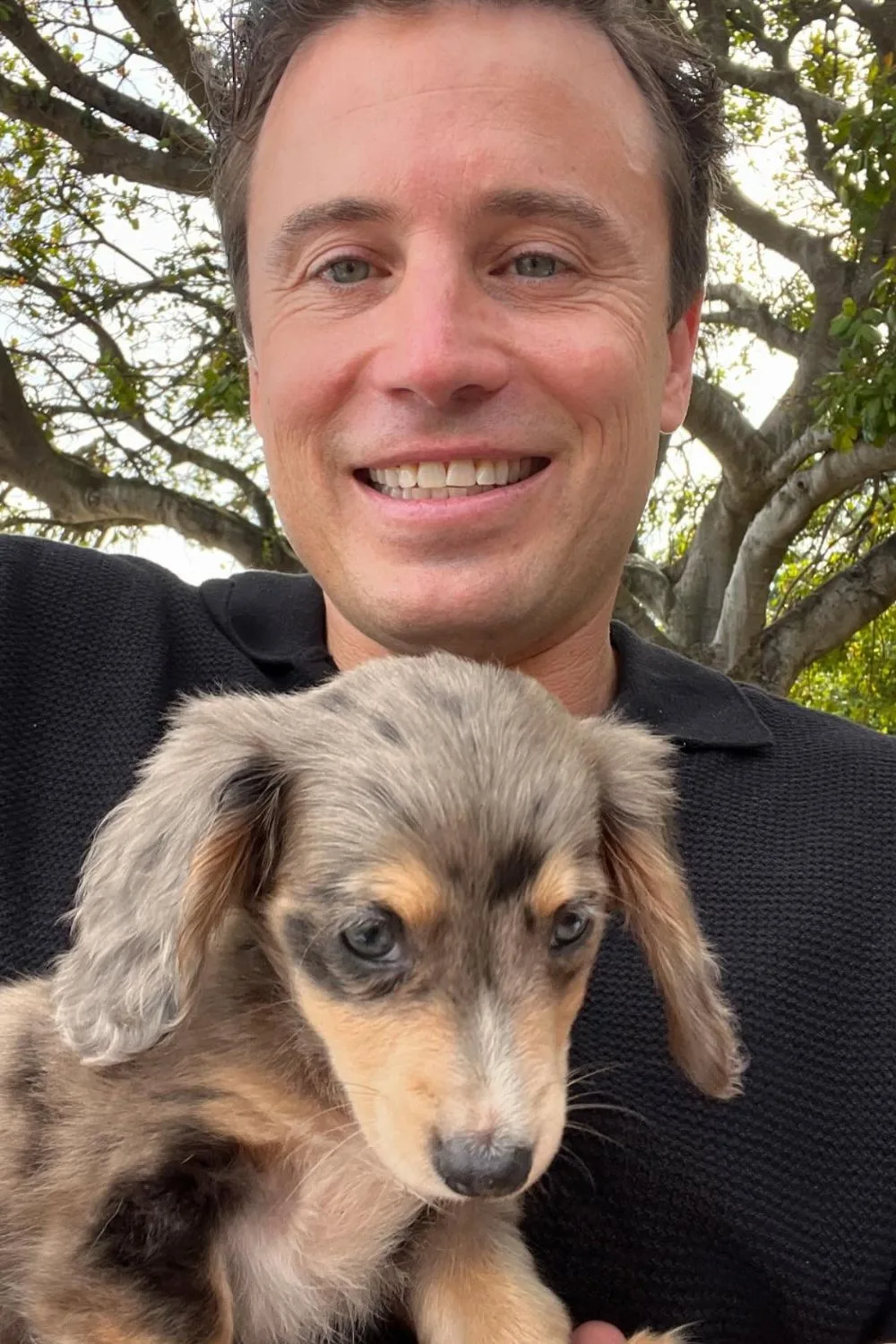 James Tobin smiles at the camera while holding a puppy
