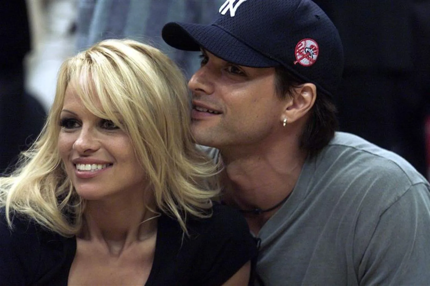 Model Marcus Schenkenberg embraces Pamela Anderson at a game