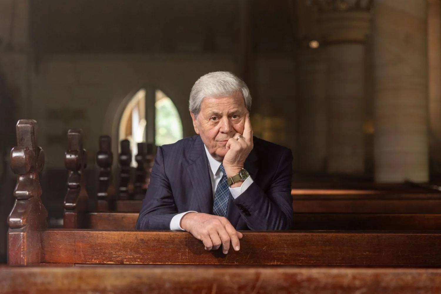 Ray Martin sits on a pew at a church in a still to promote his SBS show The Last Goodbye