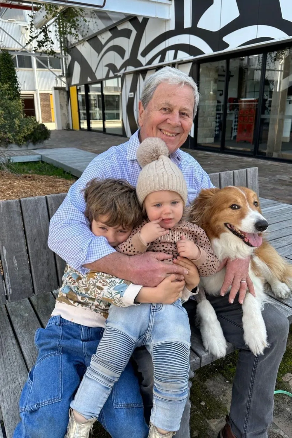 Ray Martin sits on a bench with his grandchildren and dog