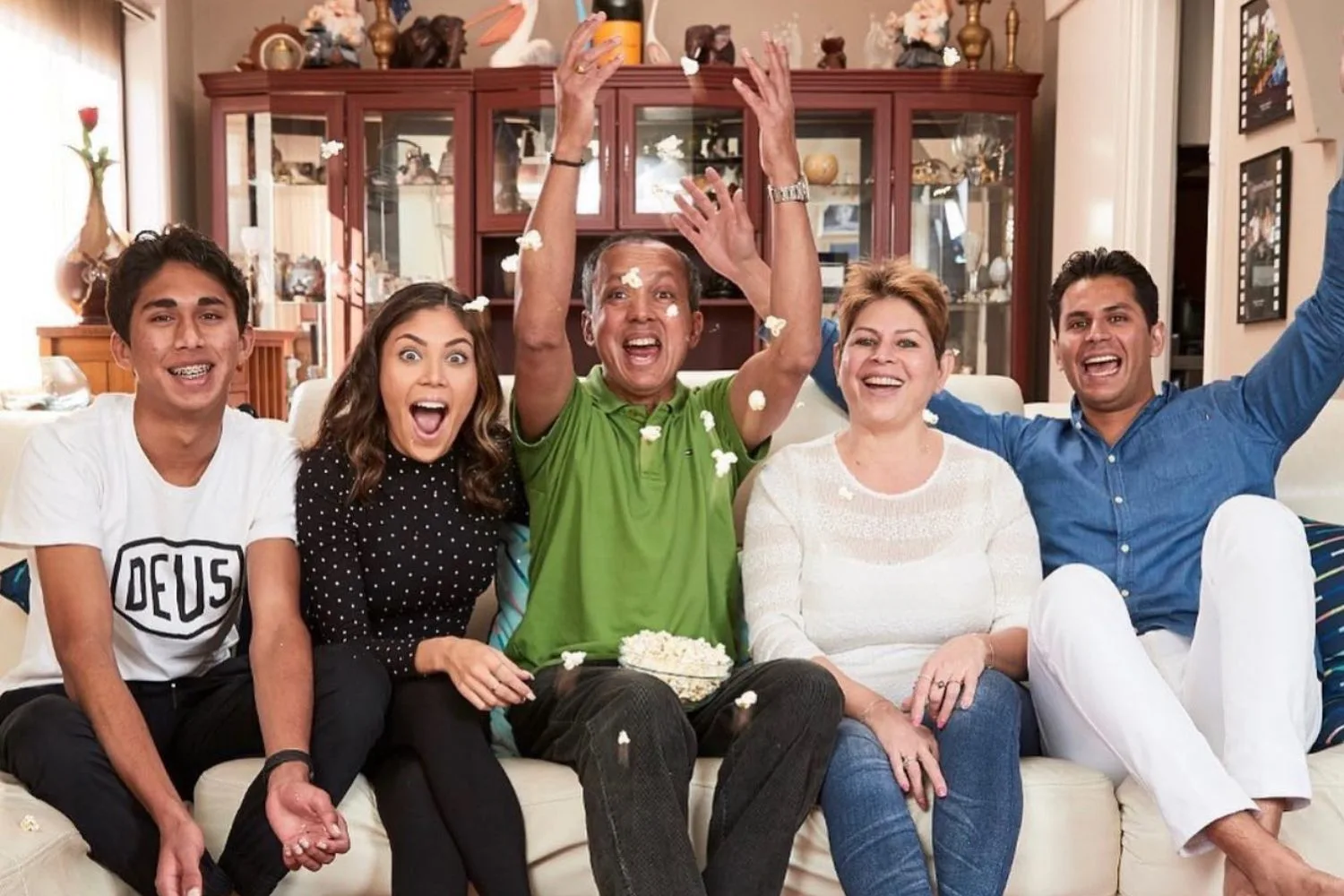 The Delpechitra family smiles as they sit on the couch together