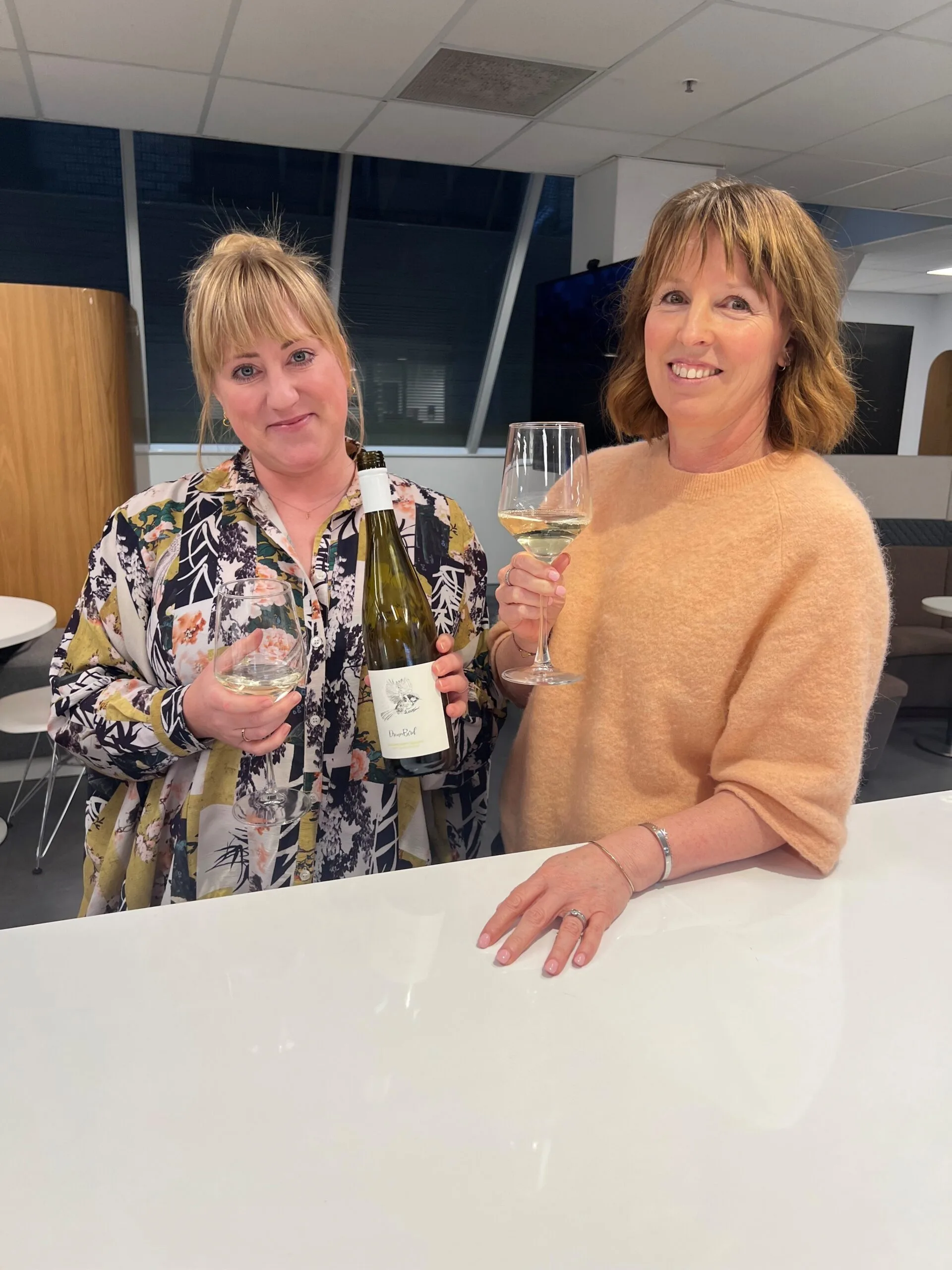 Two staffers with a wine bottle and glass