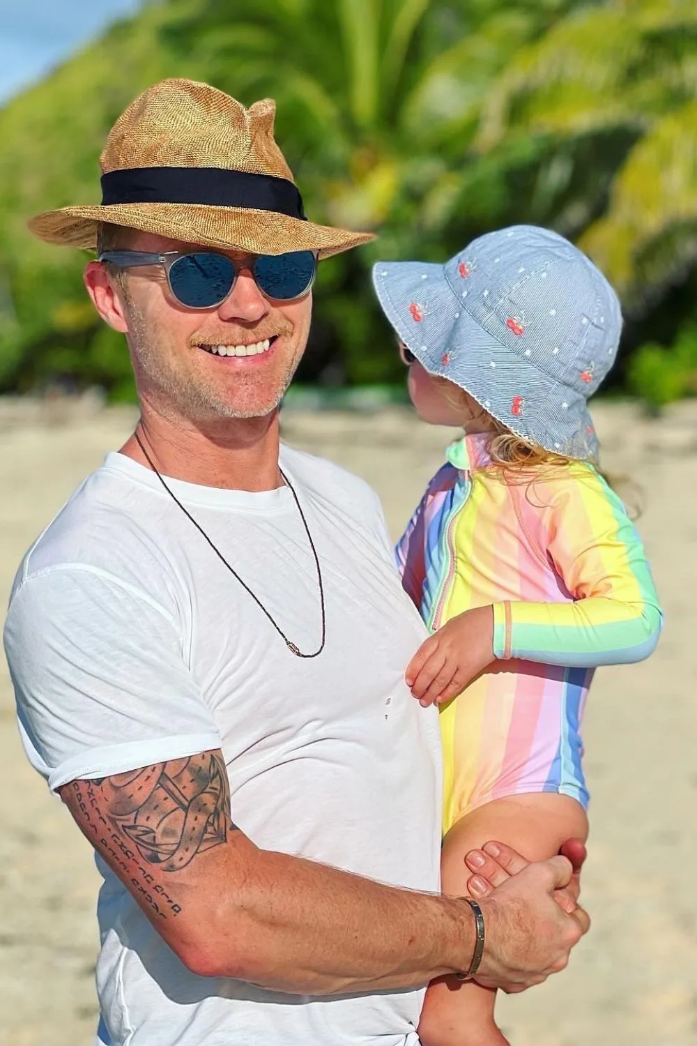 Ronan Keating at the beach holding one of his young children