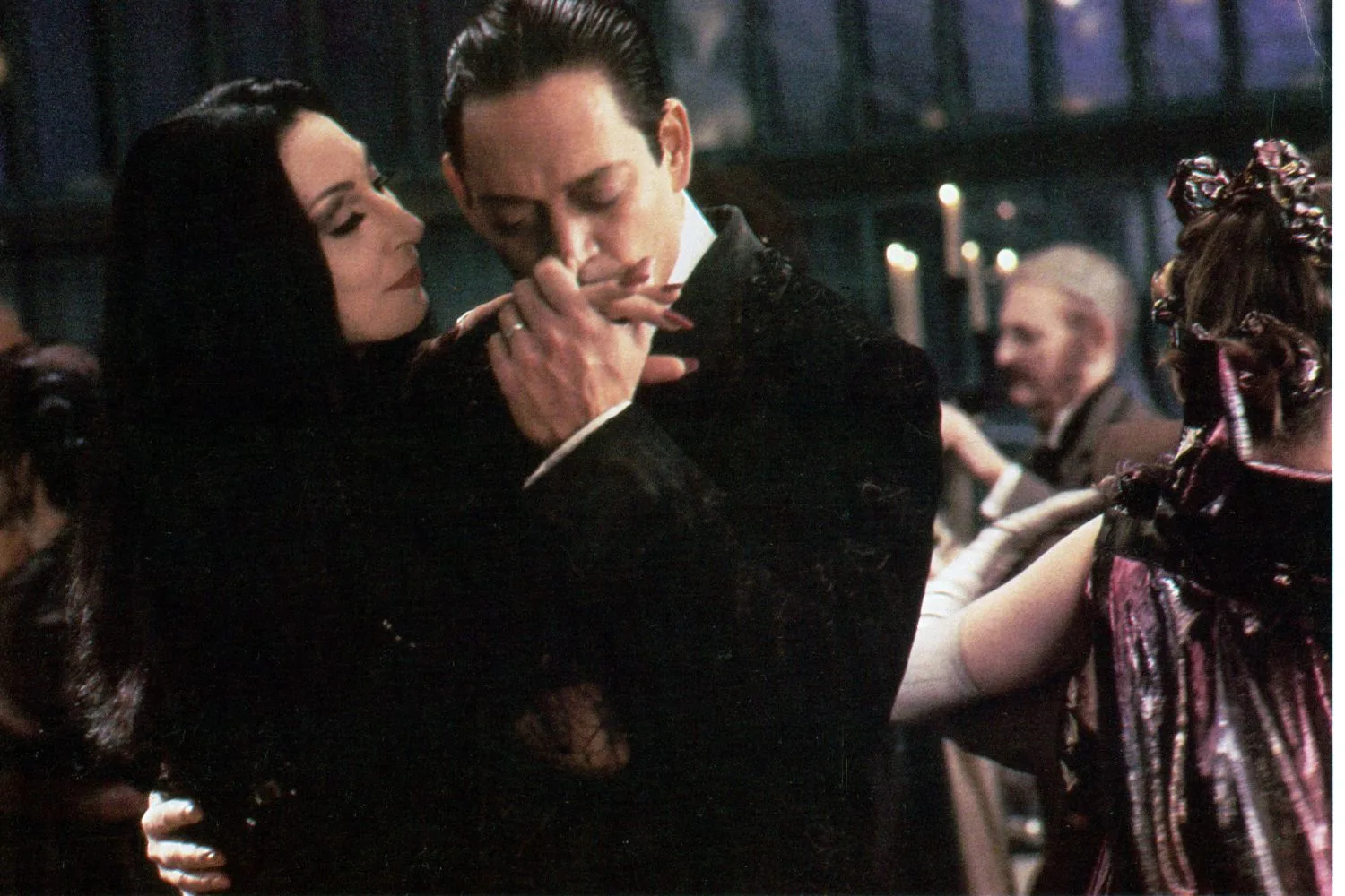 Raul Julia as Gomez Adams kisses the hand of Anjelica Huston's Morticia on The Addams Family
