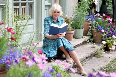 queen camilla reading a book outside in a garden