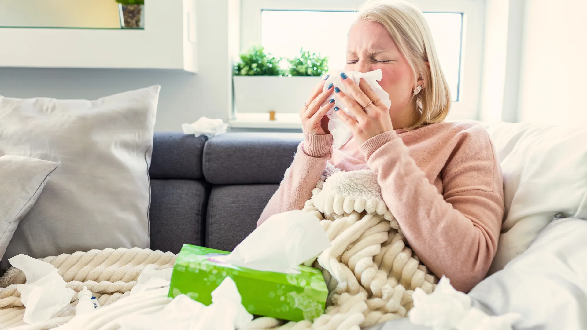 Middle aged woman sneezing into a tissue.