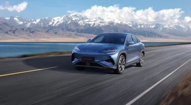 blue car driving on a road with scenic mountains in background