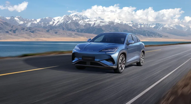 blue car driving on a road with scenic mountains in background