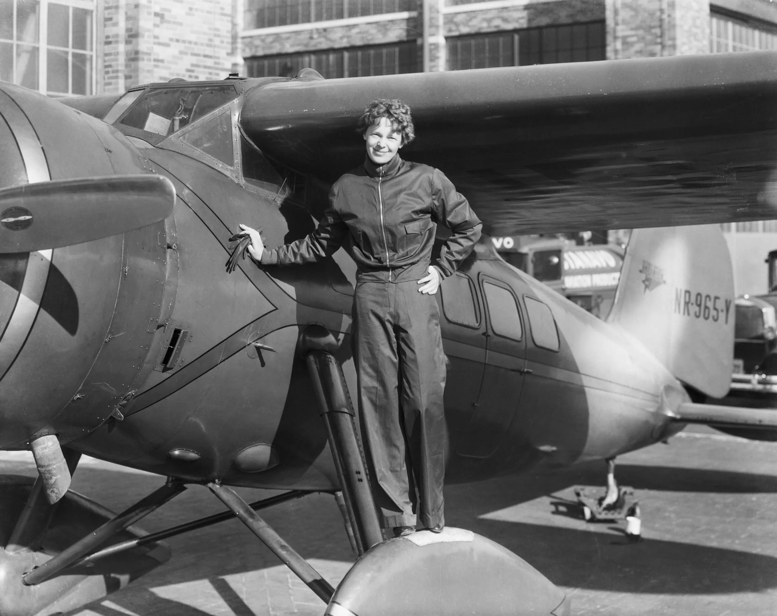 Pioneering aviator Amelia Earhart standing next to her Lockheed Electra 10E airplane.