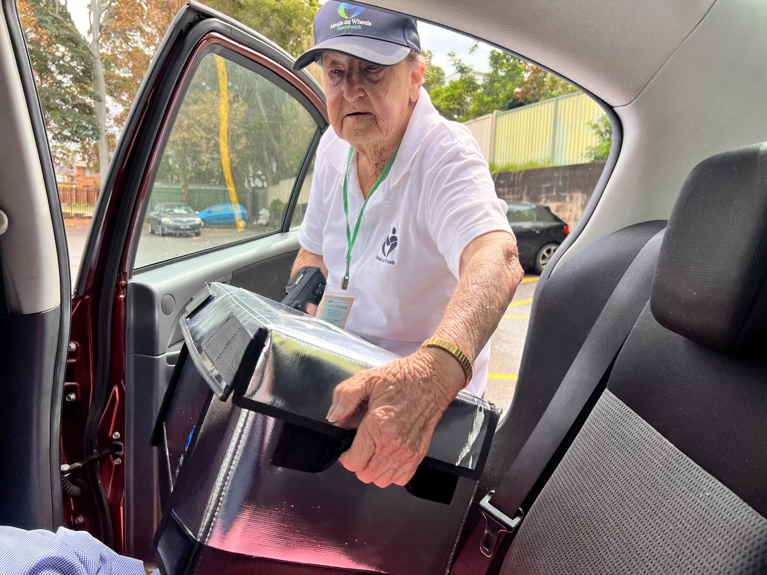 Pamela Doyle handing a meal to a Meals on Wheels client during her daily delivery run