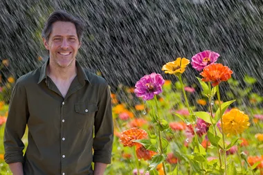 charlie albone standing in front of bright flowers in rainy weather