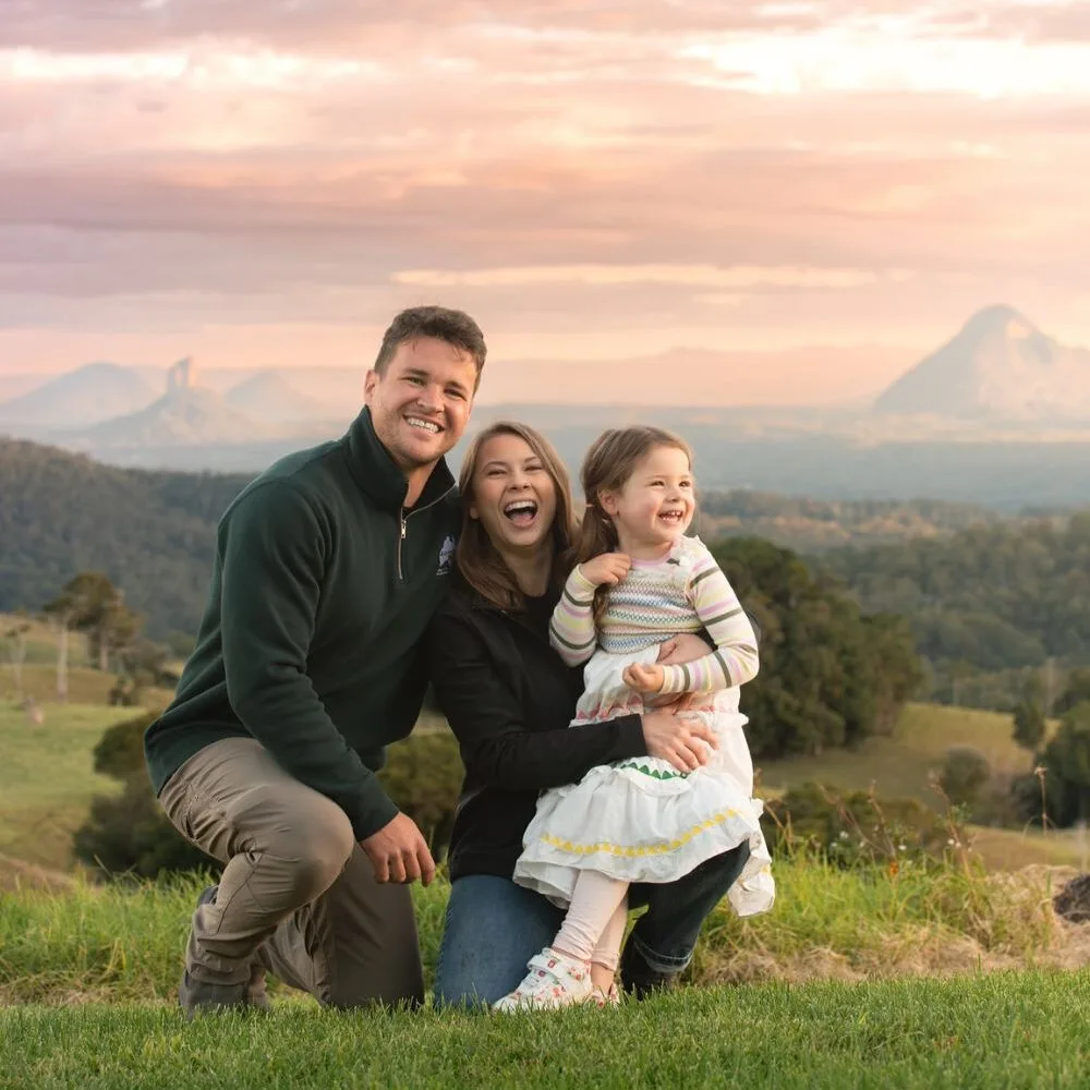 Bindi Irwin with husband Chandler and daughter Grace embracing in a field