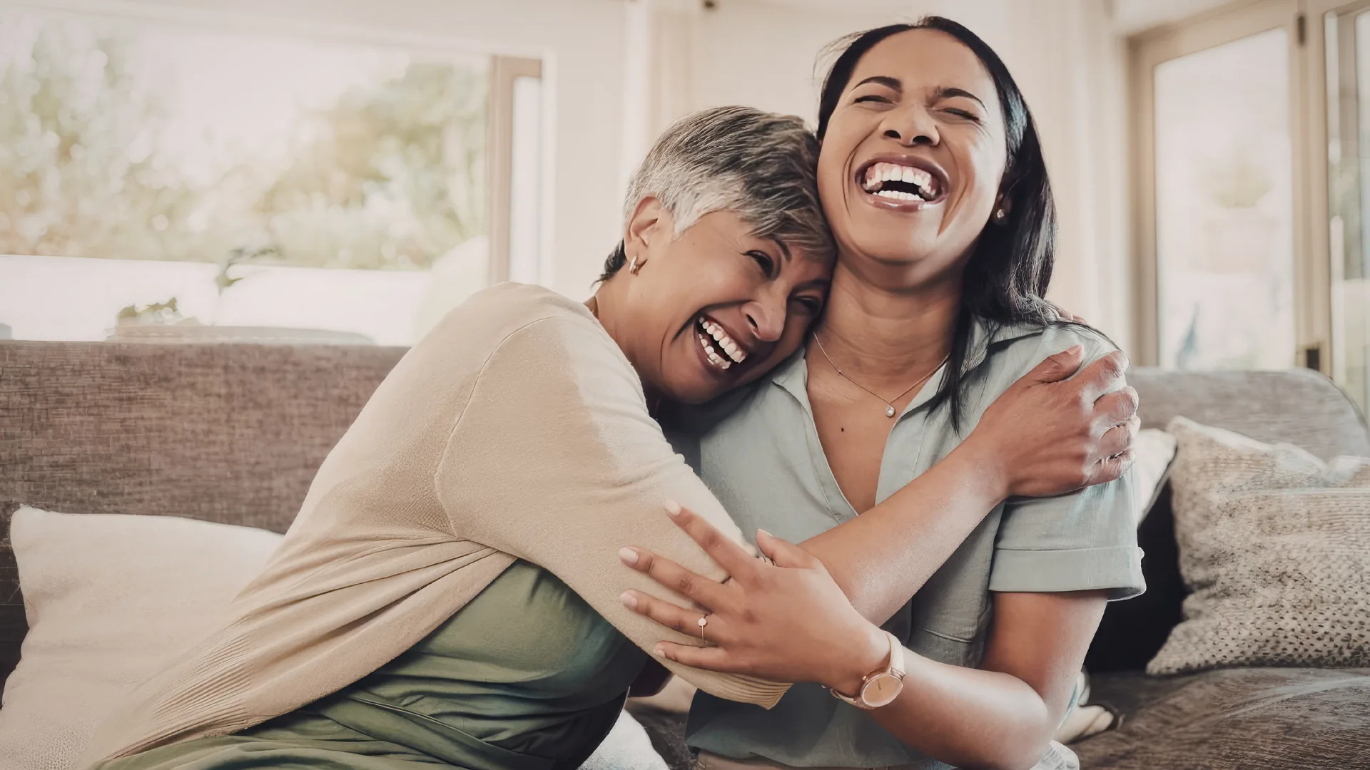 Two woman hugging and laughing on the couch