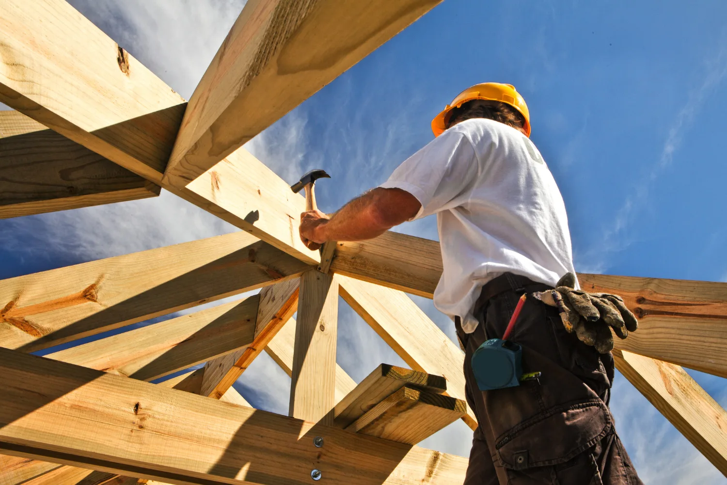 man building and hammering on contruction site