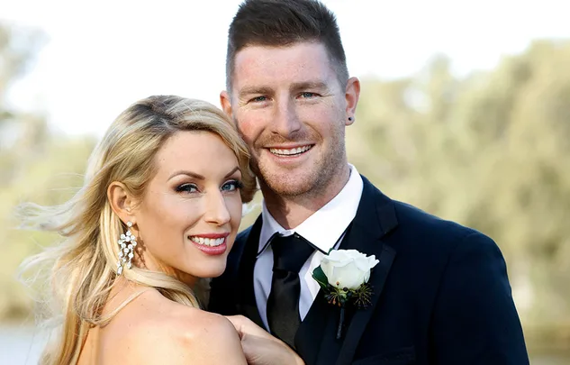 Couple smiling in formal attire with a natural outdoor background.