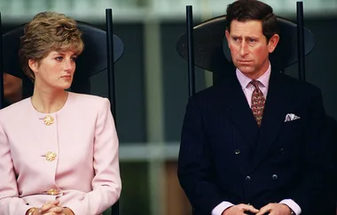 A man and woman seated, both formally dressed, looking serious.