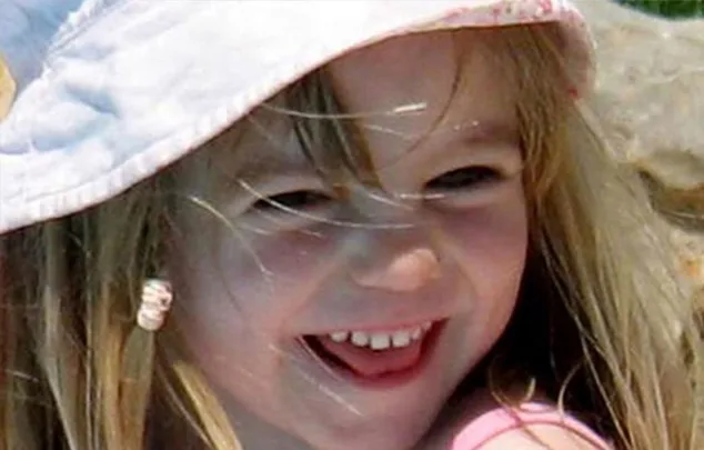 A young girl smiling, wearing a sunhat, with windblown hair, outdoors on a sunny day.