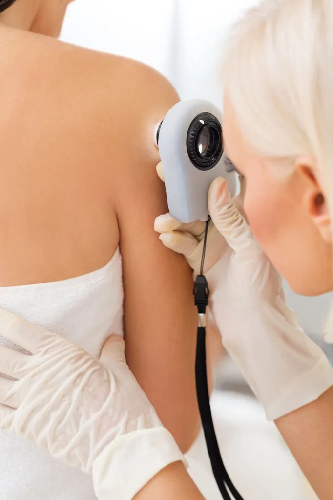 dr-checking-patients-skin-with-magnifying-glass