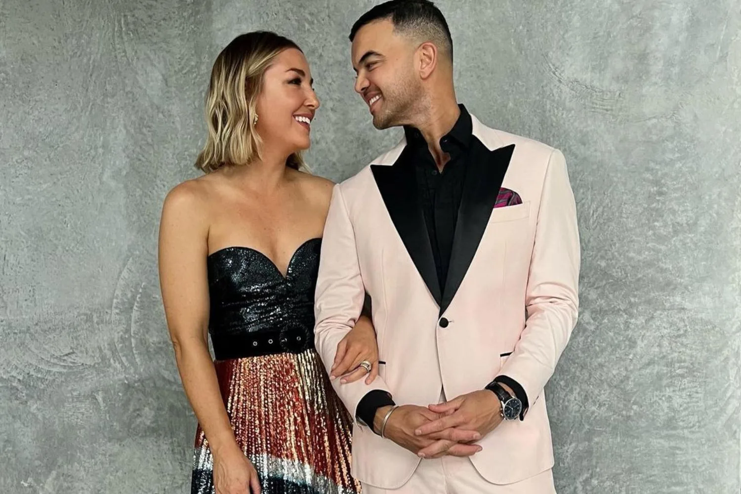 jules and guy sebastian dressed up posing for a picture as they smile at eachother lovingly