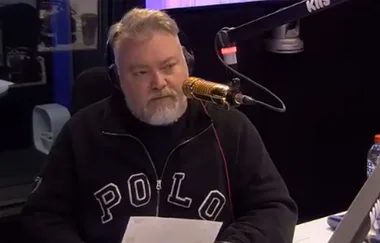 Radio host in a studio, wearing headphones, speaking into a gold microphone with "KISS" branding visible.