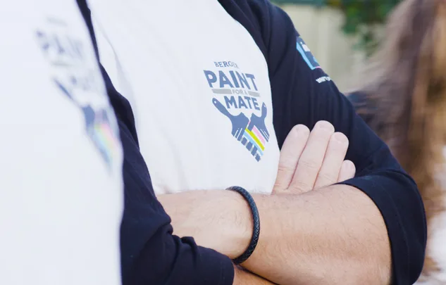T-shirt with "Berger Paint For A Mate" logo, person with arms crossed, wearing a black wristband.