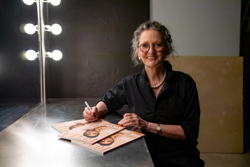 Anne Geddes sitting at desk signing her photos