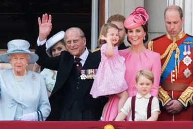 Royal family on balcony during Trooping the Colour, with children waving and smiling.