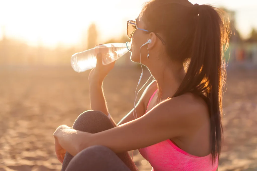 Woman drinking water on the beach